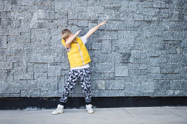 Küçük bir çocuk duvarın önünde silip eğleniyor. Boşluğu kopyala. 