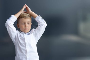 Yoga dersi sırasında elleri yukarıda meditasyon yapan küçük bir çocuk. Boşluğu kopyala. 