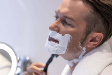 Banyoda jiletle tıraş olan bir adamın yakın çekimi..