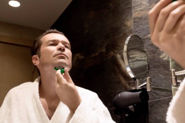 Banyoda jiletle tıraş olan bir adamın aynadaki yansıması.. 