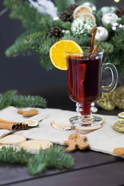 winter treats, a mug of warm wine with an orange, and cookies, ingredients on a wooden brown table. Traditional hot drink for Christmas, in the background Christmas composition.