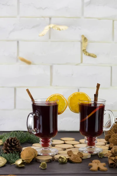 Mugs of warm wine with orange, cookies and cinnamon, dried fruit and spruce branches, hot drink for Christmas.