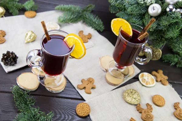 winter treats, a mugs of warm wine with an orange, and cookies, ingredients on a wooden brown table. Traditional hot drink for Christmas, in the background Christmas composition.