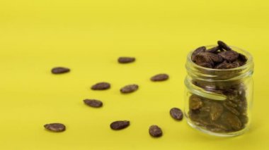 Karpuz tohumları sarı arka planda bir kavanoza dökülür.