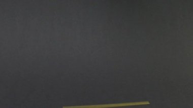 Kadın eli makarnayı makarnanın üzerine koyuyor. Siyah arkaplanda yavaş çekim