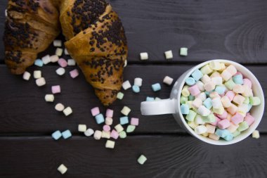 Sabah kahvaltısı, bir kupa kahve ve marshmallow, ve tahtanın üzerinde çikolatalı kruvasan.