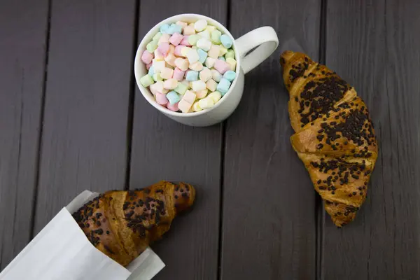 Morning breakfast with a mug of coffee and marshmallow, and a chocolate croissant on a wooden board — Stock Photo, Image