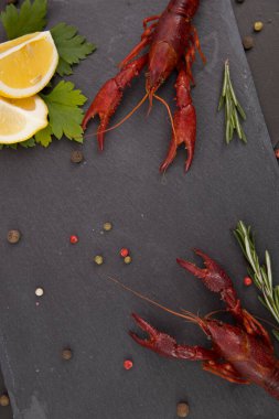 Lezzetli haşlanmış kerevit, biber, limon ve maydanozlu taş tabakta yakın plan..