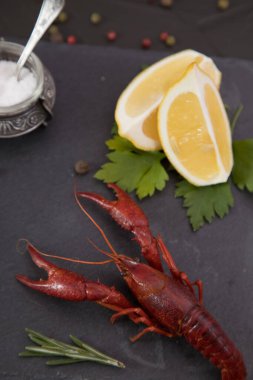 Lezzetli haşlanmış kerevit, biber, limon ve maydanozlu taş tabakta yakın plan..