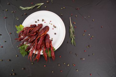 Lezzetli haşlanmış kerevit, biber, limon ve maydanozlu taş tabakta yakın plan. Metnin için boş yer. Siyah arkaplan.