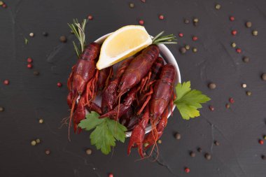 Lezzetli haşlanmış kerevit, biber, limon ve maydanozlu taş tabakta yakın plan. Metnin için boş yer. Siyah arkaplan.