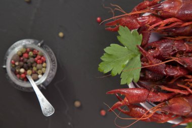 Lezzetli haşlanmış kerevit, biber, limon ve maydanozlu taş tabakta yakın plan. Metnin için boş yer. Siyah arkaplan.