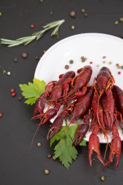 Lezzetli haşlanmış kerevit, biber, limon ve maydanozlu taş tabakta yakın plan. Metnin için boş yer. Siyah arkaplan.