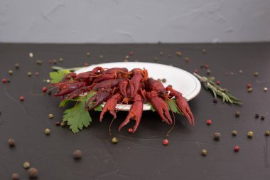 Lezzetli haşlanmış kerevit, biber, limon ve maydanozlu taş tabakta yakın plan. Metnin için boş yer. Siyah arkaplan.