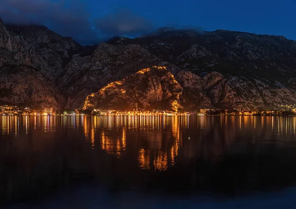 Karadağ 'ın Adriyatik Denizi kıyısındaki Kotor kentindeki dağlarda aydınlatılmış antik bir kale duvarıyla Kotor Körfezi' nin gece manzarası