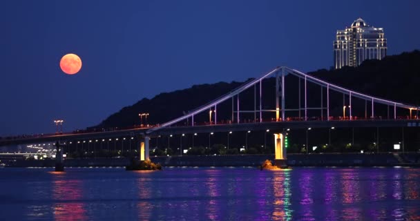 満月はウクライナのキエフ市で夜に歩行者橋の上に上昇しています — ストック動画