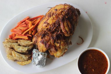 Noel, Paskalya ve diğer festivaller için hazırlanmış patates dilimleri ve sotelenmiş havuçlarla tam tavuk rostosu.