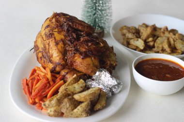 Noel, Paskalya ve diğer festivaller için hazırlanmış patates dilimleri ve sotelenmiş havuçlarla tam tavuk rostosu.