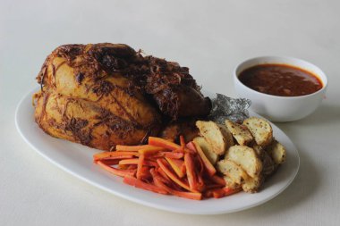 Noel, Paskalya ve diğer festivaller için hazırlanmış patates dilimleri ve sotelenmiş havuçlarla tam tavuk rostosu.