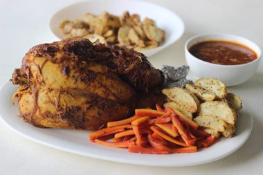 Noel, Paskalya ve diğer festivaller için hazırlanmış patates dilimleri ve sotelenmiş havuçlarla tam tavuk rostosu.