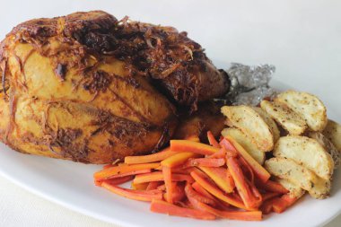 Noel, Paskalya ve diğer festivaller için hazırlanmış patates dilimleri ve sotelenmiş havuçlarla tam tavuk rostosu.