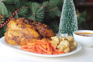 Noel, Paskalya ve diğer festivaller için hazırlanmış patates dilimleri ve sotelenmiş havuçlarla tam tavuk rostosu.