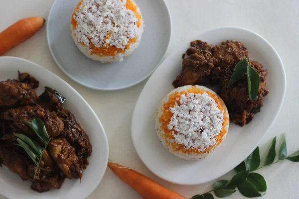 stock image Carrot puttu, a variety of Kerala rice steam cake by adding shredded carrots served along with chicken roast prepared in Kerala style with coconut oil and cocunut cut pieces.