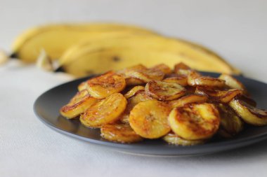 Karamelli muz dilimleri. Kerala 'dan geleneksel bir çay saati atıştırmalığı. Olgun muzu dilimlere ayır ve tencerede kızart. Kahverengi şeker de ekle. Beyaz arkaplanda çekilen.