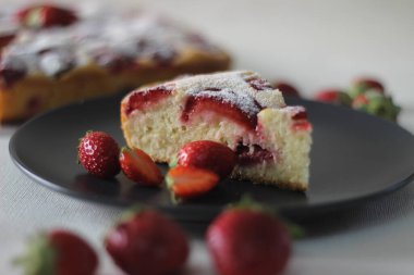 Ev yapımı çilekli pasta. Üzerine bir sürü taze çilek ve pudra şekeri serpiştirilmiş basit bir sarı pasta. Beyaz arkaplanda çekilen