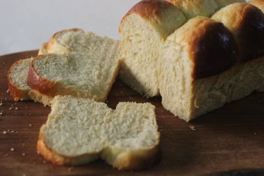 Taze pişmiş Brioche ekmeği dilimlenmiş ve ahşap bir tahtanın üzerinde duruyor. Beyaz arkaplanda çekilen.