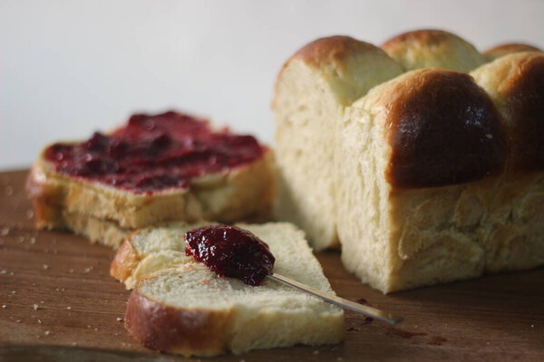 Свежеиспеченный домашний булочка булочка Бриош нарезанный и хранится на деревянной доске. Подается с вареньем. Съемка на белом фоне.