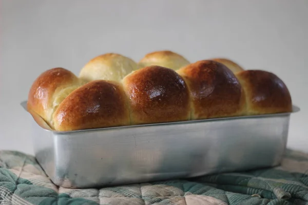 Freshly Home baked Brioche bun loaf inside the loft tin. Shot on white background.