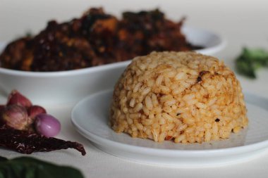 Tavuğu pişirmek için kullanılan tavaya atılmış pilav ve tavuk sosu. Pirinç kırmızı renkte görünüyor. Kerala usulü tavukla servis edilir..