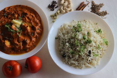 Kimyon aromalı buğulanmış basmati pilavı ve süzme peynirden yapılmış köri soslu domates, fındık ve baharatla servis edilen baharatlar. Beyaz arkaplanda çekilen
