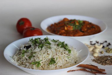 Kimyon aromalı buğulanmış basmati pilavı ve süzme peynirden yapılmış köri soslu domates, fındık ve baharatla servis edilen baharatlar. Beyaz arkaplanda çekilen