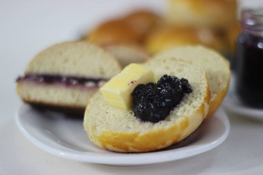 Yumuşak ve yumuşak Brioche çörekleri, süt, tereyağı ve yumurtalarla zenginleştirilmiş bir Fransız maya ekmeği. Japon Tangzhong metodu kullanılarak yapılır. İkiye bölünmüş ve üzüm reçeli ve tereyağıyla servis edilmiş.