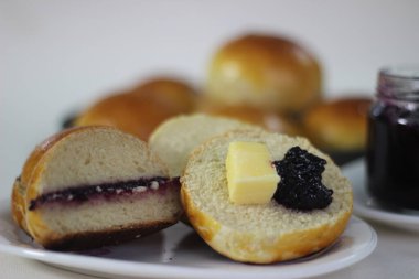 Yumuşak ve yumuşak Brioche çörekleri, süt, tereyağı ve yumurtalarla zenginleştirilmiş bir Fransız maya ekmeği. Japon Tangzhong metodu kullanılarak yapılır. İkiye bölünmüş ve üzüm reçeli ve tereyağıyla servis edilmiş.