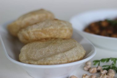 Tüylü tam buğday ekmeği ve yanında baharatlı nohut sosu. Yerel olarak Chole puri olarak bilinir. Beyaz arkaplanda çekilen