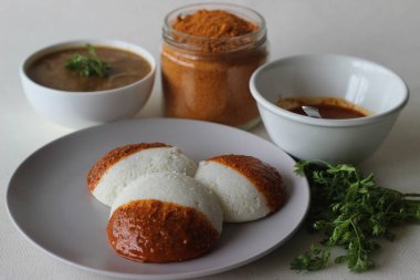 Idli 'nin yarısı podi turşusuyla kaplı ayrıca barut olarak da adlandırılıyor. Podi zemin darbelerinden, kurutulmuş kırmızı biberlerden ve biberlerden oluşur. Beyaz arkaplanda çekilen