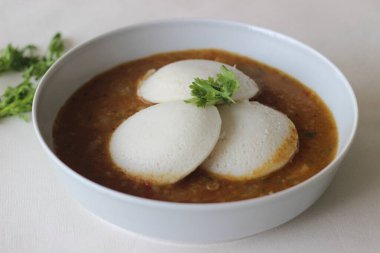 Idli Sambhar genellikle Güney Hindistan 'da üretilen ama Hindistan' ın neredeyse her yerinde sevilip hazırlanan bir Hint yemeği. Güzelce kaplanmış. Beyaz arkaplanda çekilen