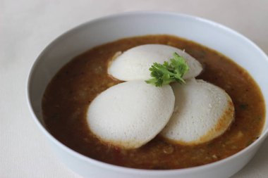 Idli Sambhar genellikle Güney Hindistan 'da üretilen ama Hindistan' ın neredeyse her yerinde sevilip hazırlanan bir Hint yemeği. Güzelce kaplanmış. Beyaz arkaplanda çekilen