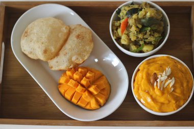 Puri, mango hamuru ve patates masala ile servis edildi. Yerel olarak Puri Masala ve Aamras olarak bilinir. Yaz boyunca popüler Kuzey Hint yemekleri.