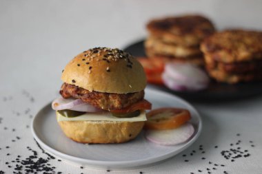 Tavuk burger. Ev yapımı tavuk köftesi, soğan, jalapeno ve peynirli ev yapımı hamburger ekmeği. Beyaz arkaplanda çekilen
