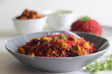 Pancar pulao, bir tencere pilav, basmati pilavı, pancar kökü, soğan ve baharatlı. Kızarmış tavuk ısırığı ve kaymak ile servis ediliyor. Beyaz arkaplanda çekilen