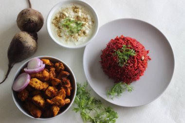 Pancar pulao, bir tencere pilav, basmati pilavı, pancar kökü, soğan ve baharatlı. Kızarmış tavuk ısırığı ve kaymak ile servis ediliyor. Beyaz arkaplanda çekilen