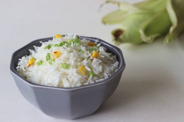 Üzerine taze soğan ve mısır serpiştirilmiş buğulanmış beyaz pirinç. Sağlıklı ve hızlı bir öğle yemeği. Beyaz arkaplanda çekilen