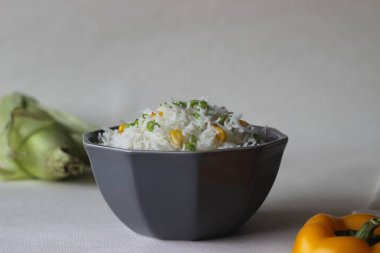 Üzerine taze soğan ve mısır serpiştirilmiş buğulanmış beyaz pirinç. Sağlıklı ve hızlı bir öğle yemeği. Beyaz arkaplanda çekilen