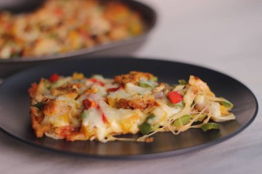 Peynir, tavuk ve sebzelerle dolu ince hamurlu ev yapımı bir pizza. Beyaz arkaplanda çekilen.