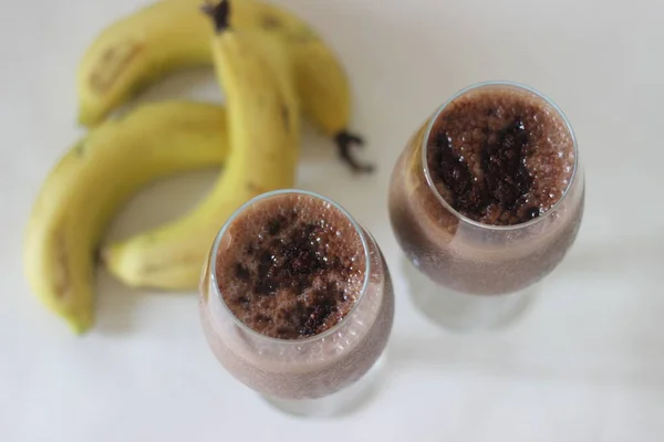 Chocolate banana milkshake made with frozen bananas, cocoa and chilled milk. Shot on white background.