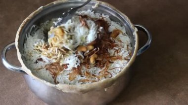 Mühürlü kenarları kırdıktan sonra açık tencerede buharlı koyun biryani 'si. Pirinci yavaş pişirmek için kenarları satıldı. Hint yemeği olan biryani 'yi hazırlamak için kullanılan bir yöntem..